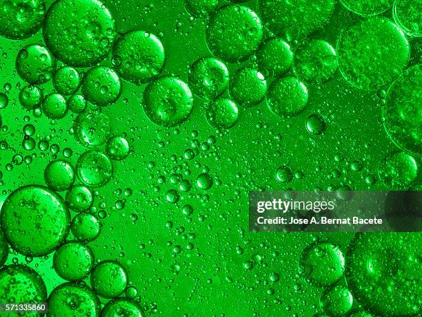 oil drops and bubbles floating over water with a green background - exploding glass 個照片及圖片檔