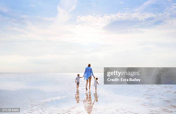 mother and children walking at low tide sunset. - enfants plage photos et images de collection