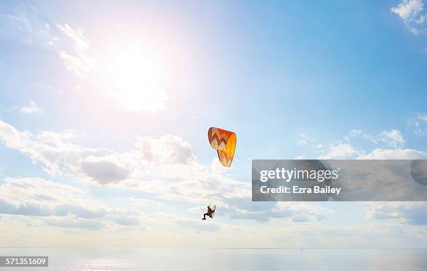 a man using a powered paraglider over the sea - parapente fotografías e imágenes de stock