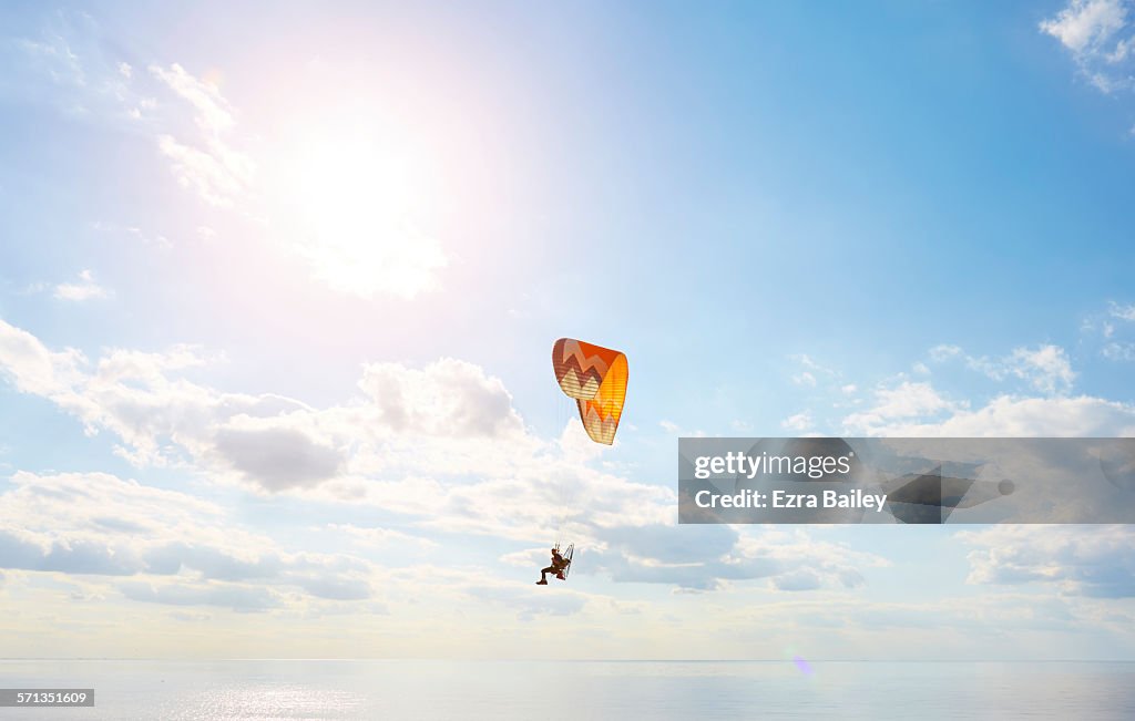 A man using a powered paraglider over the sea