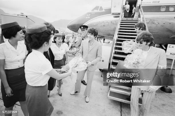 The Beatles receive welcome bouquets from the staff at Hong Kong International Airport during their Asian tour, 3rd July 1966. Their aircraft stopped...