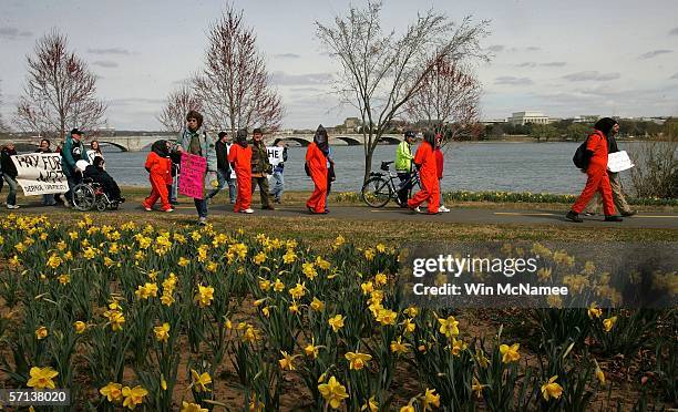 Hooded protesters dressed in orange prisoner of war jumpsuits are led along the bank of the Potomac River on their way to the Pentagon to seek an...