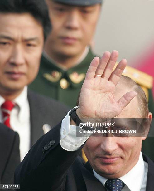Visiting Russian President Vladimir Putin waves on arrival at the airport in Beijing, 21 March 2006, followed by Chinese government and military...