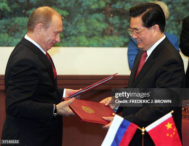 Visiting Russian President Vladimir Putin and Chinese President Hu Jintao exchange signed documents following a signing ceremony at the Great Hall of...