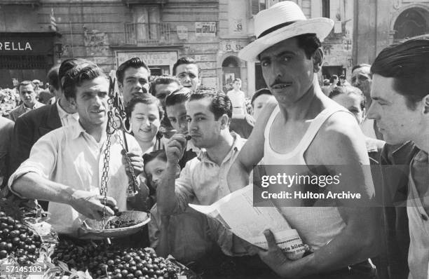 Man sells cherries from a market stall in Naples, circa 1952.