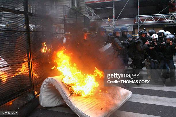 Mattress burns in front of a fence protecting riot policemen from demonstrators during a rally against the First Employment Contract , 21 March 2006...