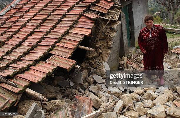 Woman walks over rubble 21 March 2006 in the town of Bejaia after an earthquake hit the nearby town of Laalam in northeast Algeria, killing three...