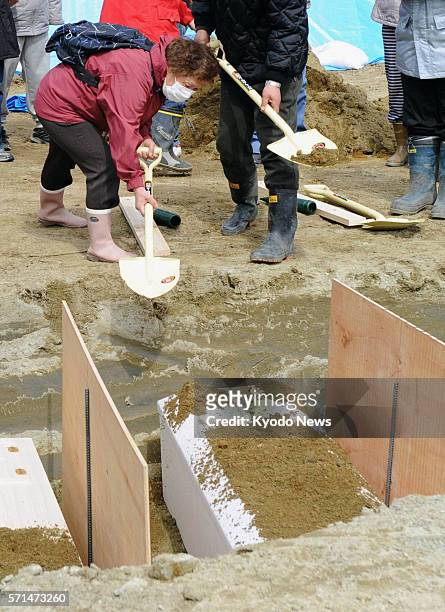 Japan - A woman shovels dirt on the coffin of a victim of a massive earthquake and tsunami in Higashimatsushima, Miyagi Prefecture, on March 22,...
