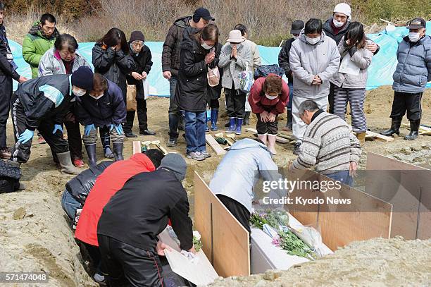 Japan - Bereaved families and friends take part in the burial of those killed in the March 11, 2011 massive earthquake and tsunami, in...