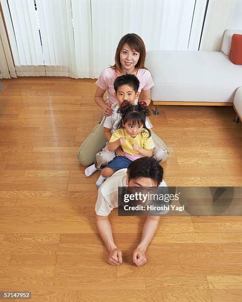 a woman along with her two children sitting on her husband's back - lying on back girl on the sofa stock-fotos und bilder