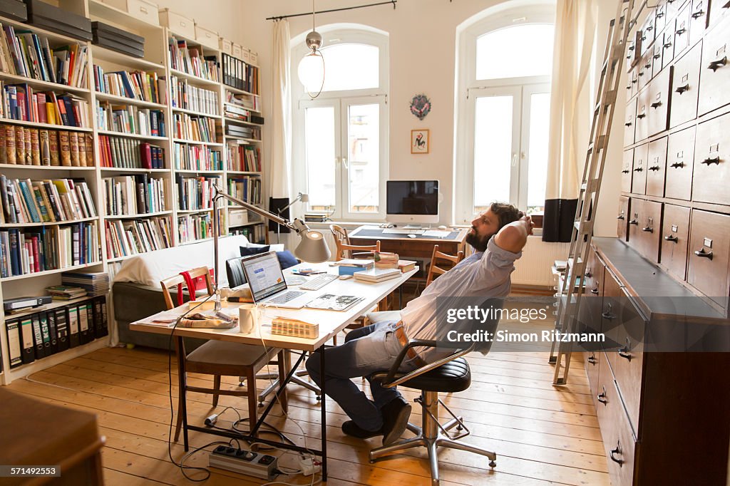 Young designer relaxing in home office.