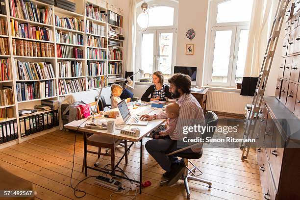 male and female designer at work with two children - telecommuting couple stock pictures, royalty-free photos & images