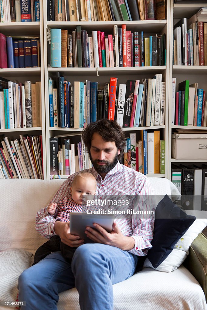 Young father with baby son using tablet computer