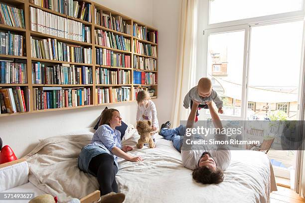 young family playing on bed - child in bed clothed stock-fotos und bilder