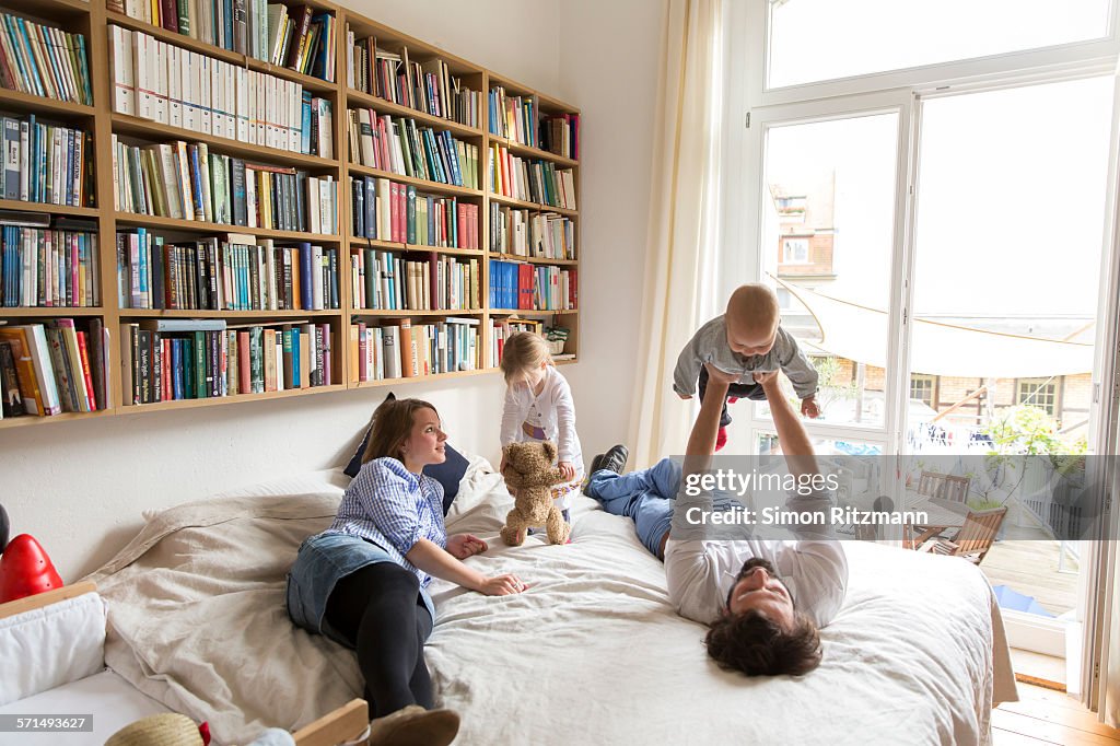 Young family playing on bed