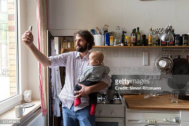 father with baby son taking selfie with smartphone - leanincollection stock pictures, royalty-free photos & images