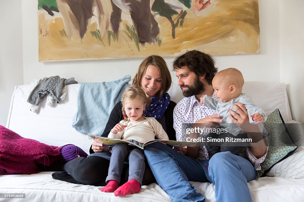 Young family reading storybook together on sofa