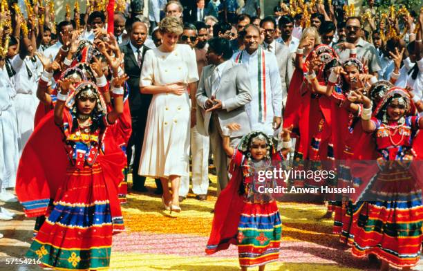 Diana, Princess of Wales, wearing a cream dress, with a pleated skirt and gold buttons designed by Catherine Walker, watches a tribal Lambadi dance...