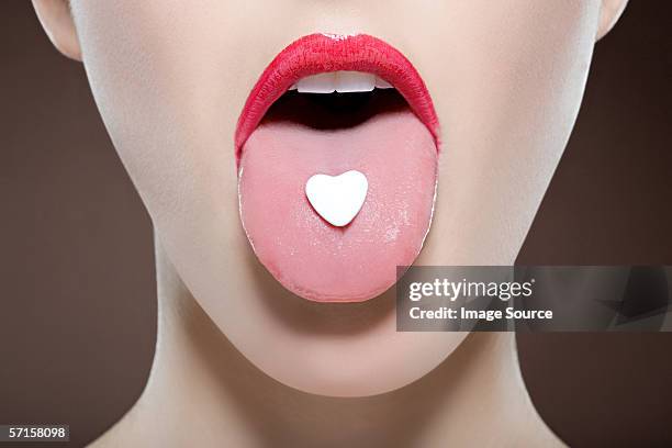 woman with heart sweet on her tongue - candy on tongue stock pictures, royalty-free photos & images