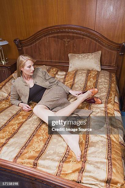 geschäftsfrau auf dem bett in hotelzimmer - entkleiden stock-fotos und bilder