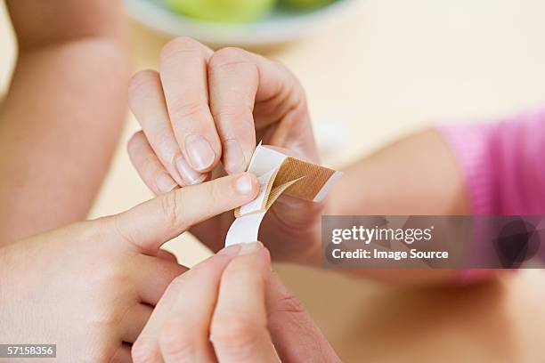 mutter putting verputz auf kind finger - pflaster stock-fotos und bilder