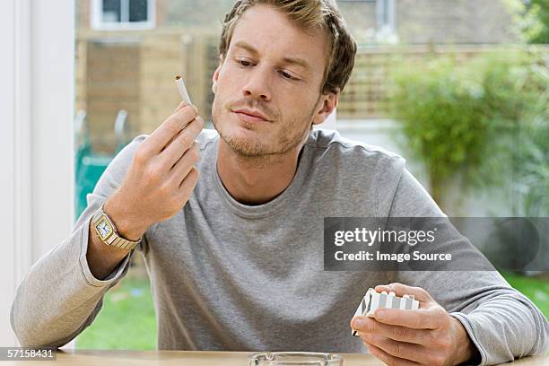 man looking at a cigarette - cigarette pack stockfoto's en -beelden