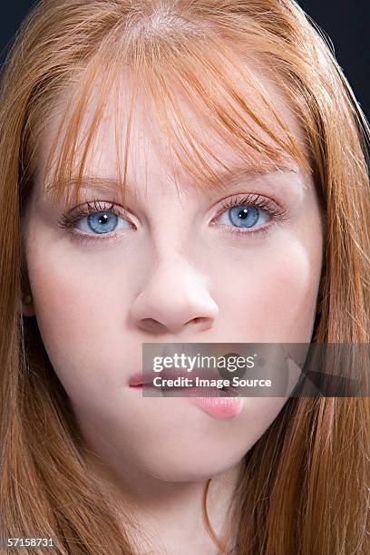 young woman with red hair biting lip - biting lip stock pictures, royalty-free photos & images