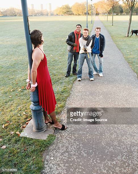 man handcuffed to lamp post being laughed at - fuzzy handcuffs stock pictures, royalty-free photos & images