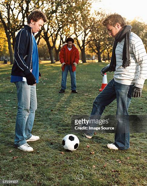 men playing football in park - passing - sport stock pictures, royalty-free photos & images