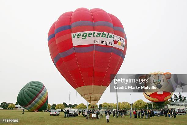 Hot air balloons slowly inflate with "Honey Bear" piloted by Ryan "Rowdey" Smith of America in the background during a wet Mass Ascension on day one...