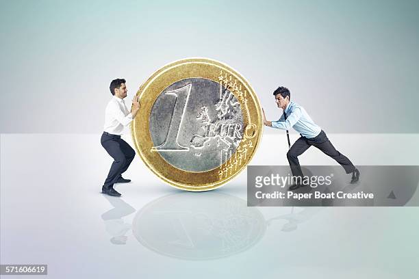 two businessmen pushing a giant euro coin - euro championship stock pictures, royalty-free photos & images