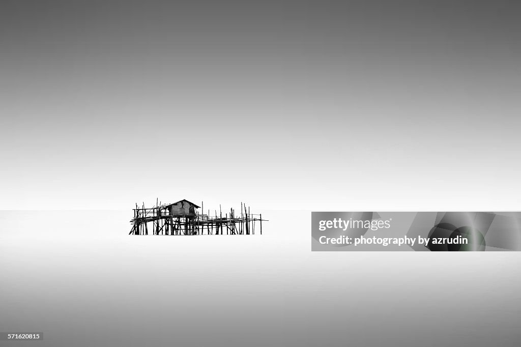 Isolated cottage with poles on the sea