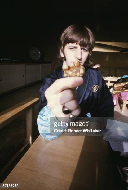 Ringo Starr seems confused by a small carving whilst visiting Tokyo during the Beatles' Asian tour, 1966.
