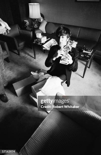 John Lennon opens a gift at the Tokyo Hilton during the Beatles' Asian tour, 1966.