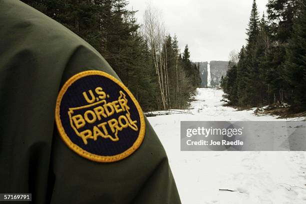 Border Patrol agent stands along the boundary marker cut into the forest marking the line between Canadian territory on the right and the United...