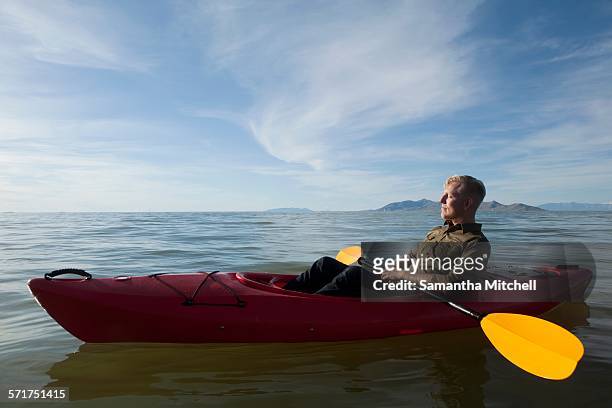 side view of young man in kayak on water holding paddles, eyes closed, great salt lake, utah, usa - sea kayaking stock-fotos und bilder