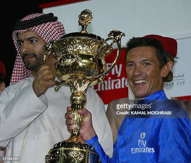 Dubai, UNITED ARAB EMIRATES: Emirati trainer Saeed bin Srour poses with Italian jockey Lanfranco Dettori who is displaying the Dubai World Cup trophy...