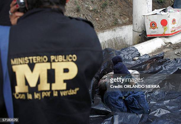 Una fiscal del Ministerio Publico observa el cadaver de un hombre, encontrado maniatado, con el tiro de gracia y envuelto en nylon, en el anillo...