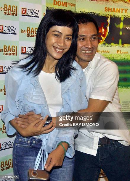The director of "Berbagi Suami" , Nia Dinata poses in front of a large poster of the film during the launching in Jakarta 21 March 2006 with one of...