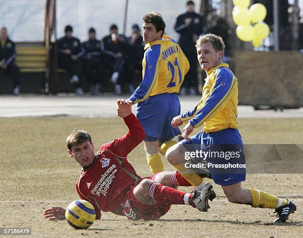 Maxim Astafiev of Luch-Energia clashes with Bronislav Ivanovich of Lokomotiv as Ruslan Adzindzal of Luch-Energia looks on during the Russian Football...