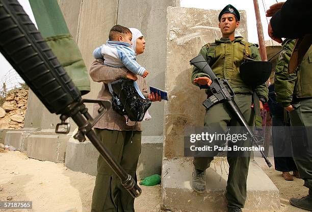Palestinian woman holds a child as she argues with Israeli soldiers while trying to go across the wall from Abu Dis, West Bank on March 26, 2006 into...