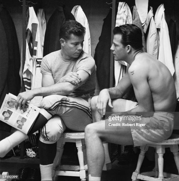 American football players Kyle Rote and Frank Gifford of the New York Giants sit on stools as they chat in the locker room prior to the start of the...