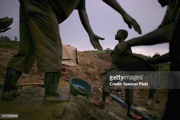 Men pass buckets of dirt which they will sift through while looking for gold March 27, 2006 in Mongbwalu, Congo. Thousands of Congolese scrape...