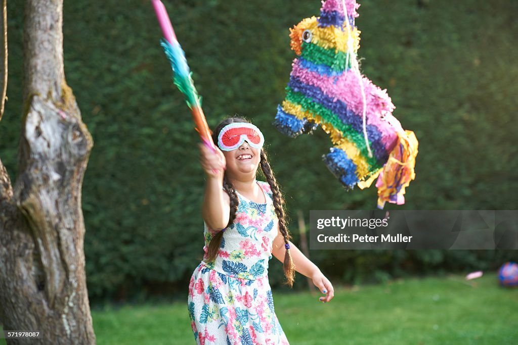 Girl playing pinata in garden