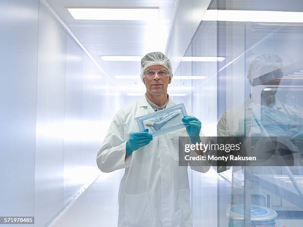 worker holding orthopaedic hip stem replacement in clean room, portrait - hip replacement stock pictures, royalty-free photos & images