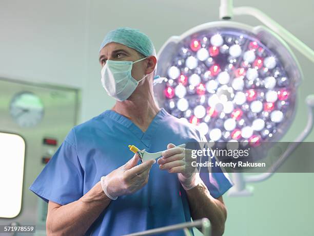 orthopaedic surgeon in operating theatre with replacement hip stem - hip replacement stock pictures, royalty-free photos & images