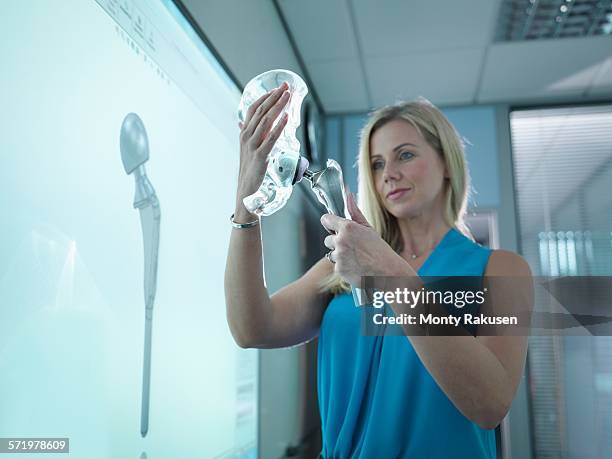 medical product designer inspecting hip joint model with graphical screen - hip replacement stock pictures, royalty-free photos & images
