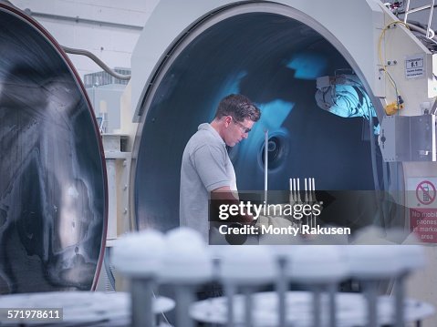 Engineer with ceramic coating machine, coating artificial hip joints in orthopaedic factory Engineer with ceramic coating machine, coating artificial hip joints in orthopaedic factory