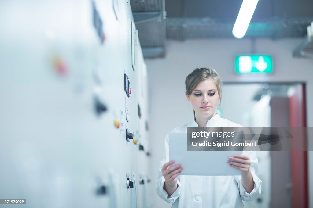 Young female scientist reading paperwork in technical room