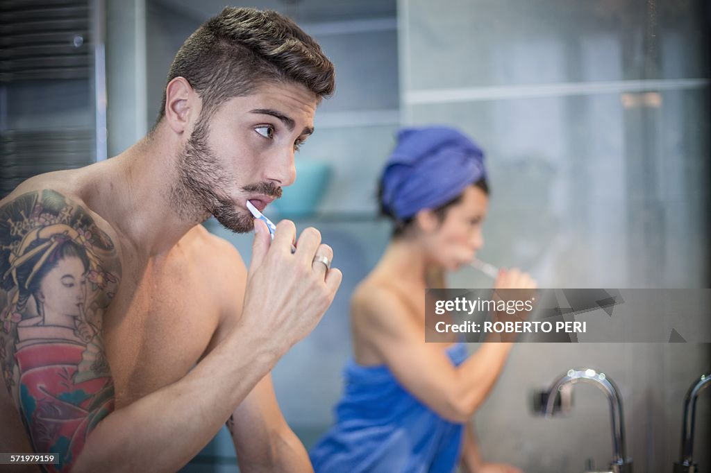 Young couple brushing teeth in bathroom